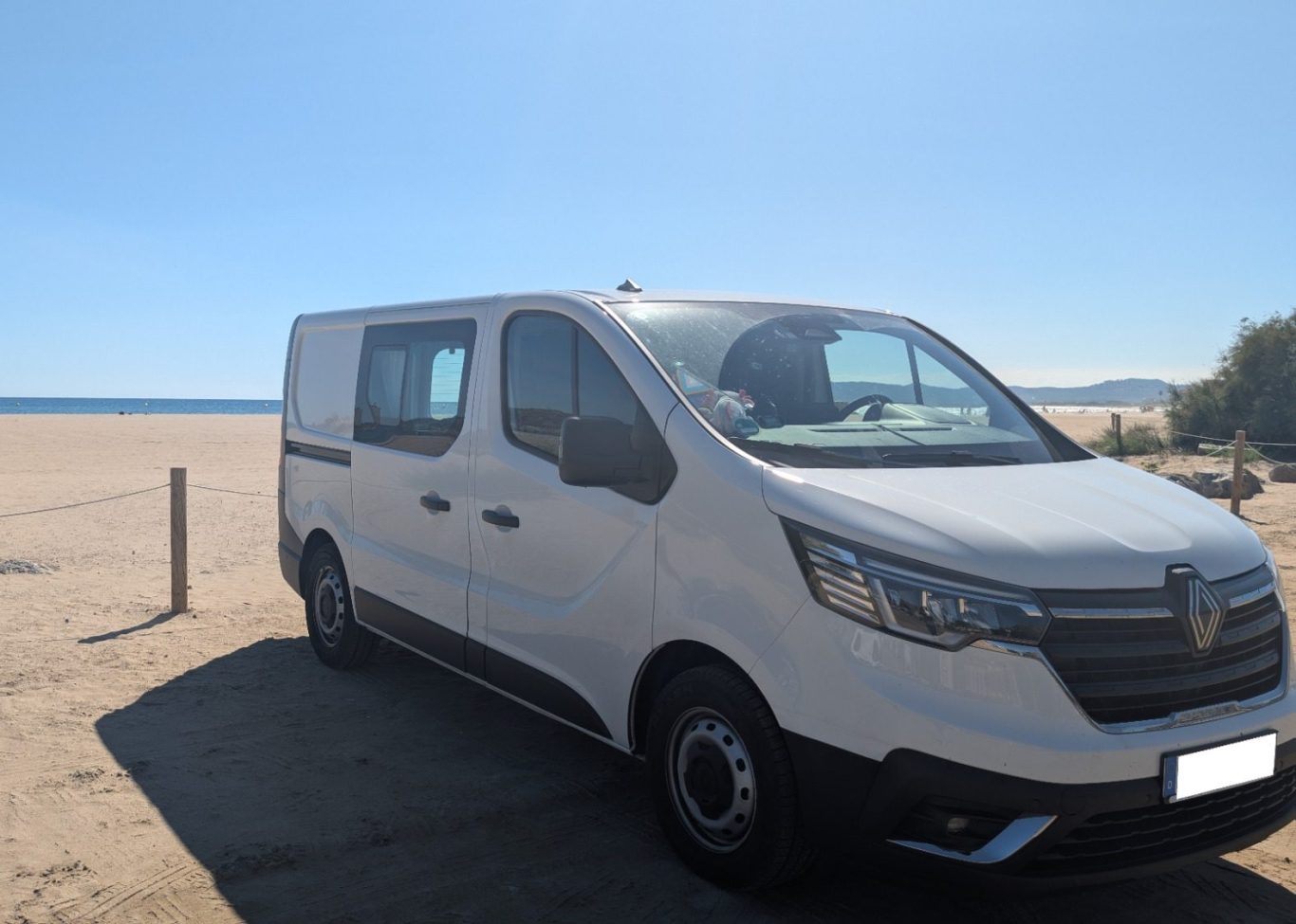 Weißer Renault Trafic, selbstausgebauter Camper am Strand an der Costa Brava, ein Symbol für Paarziele und Freiheit
