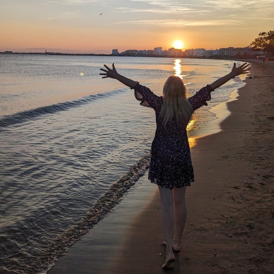 Silhouette einer Person am Strand mit ausgebreiteten Armen zum Sonnenuntergang – Symbol für Freiheit, neue Perspektiven und Visionen